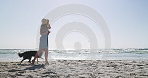 Travel, dog and relax with woman at the beach for vacation, freedom and nature. Pets, holiday and training with person