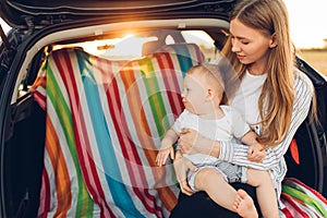 Travel - family ready to go on summer vacation, Happy mom with a small child in the trunk of a car