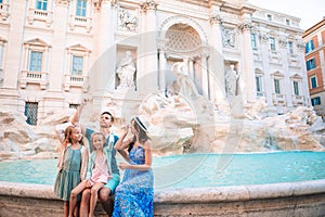 Travel family trowing coin at Trevi Fountain, Rome, Italy for good luck.