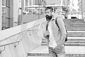 Travel free with technology. Bearded man listen to music urban outdoors. Hipster wear headphones in casual style. New