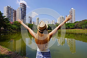Travel in Goiania, Brazil. Back view of girl with raising arms in the city park Vaca Brava in Goiania, Goias, Brazil photo