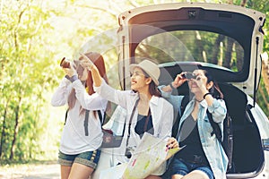 Travel group asian woman traveler sitting on hatchback car for trip road with outdoors forest in vacations