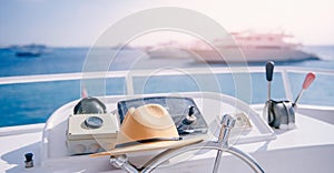 Travel hat lies on steering wheel of modern luxury yacht with sun light, concept banner trip on sea, boat rental.