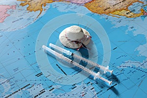 Travel hats and disposable syringes on top of the world map.