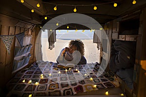 Travel and independent lifestyle concept with young beautiful curly free lady reading a book outside her hand made vintage wooden