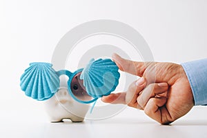 Travel insurance concept.business insurance agent hand in gesture of protection of piggy bank with shell sunglasses on white back