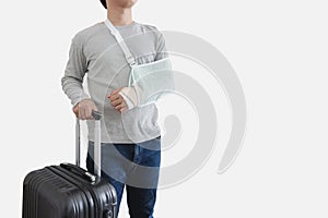 Travel insurance concepts. Young man with hand injured wearing splint, broken arm, holding black baggage,