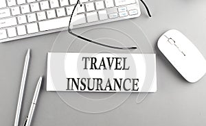 TRAVEL INSURANCE text on paper with keyboard on grey background