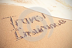 Travel Insurance text written on sand