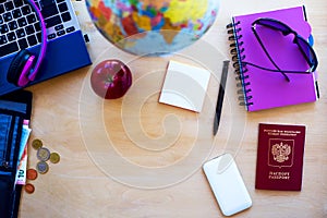 Travel items, passport, pen, pc, globe, apple, money on wooden b