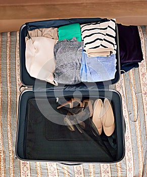 Travel, luggage and clothes in suitcase for holiday or vacation packing in bedroom from above. Adventure, bag and