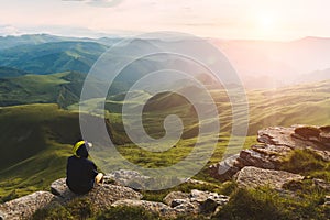 Travel man tourist sitting alone on the edge mountains over green valley adventure lifestyle extreme vacations green landscape