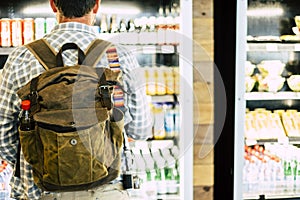 Travel man viewed from back in front of an automatic drink store choosing snacks or beverage before leave or start the business or