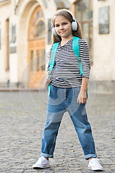 Travel means learning. Little kid carry travel bag listening to music outdoors. Educational school trip. Tourism