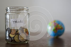 Travel money savings in a glass jar with earth globe on the background