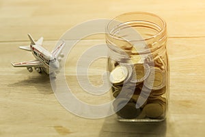 Travel money savings in a glass jar and put on wooden present budgets in holiday.