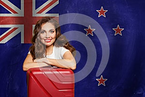 Travel in New Zealand concept. Happy woman with suitcase on flag of New Zeland. Welcome to New Zeland