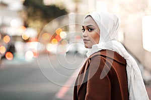 Travel with no regrets. an attractive young woman wearing a hijab and standing alone while touring the city.