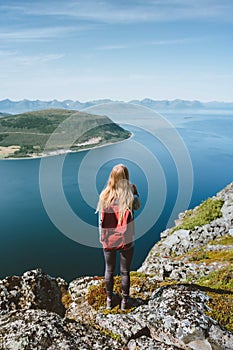 Travel in Norway woman traveler with backpack standing on cliff alone