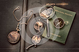 Travel, passport, compass, watch, glasses and magnifier on a vintage geographical atlas for exploration and adventure