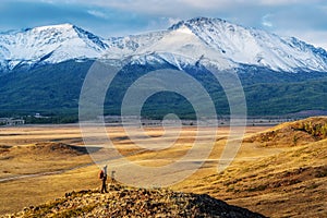 Travel photographer on a hilltop in the Kurai steppe, view of the North Chuysky ridge