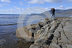 Travel photographer photographing Tessellated Pavement in Tasman Peninsula Tasmania Australia photo