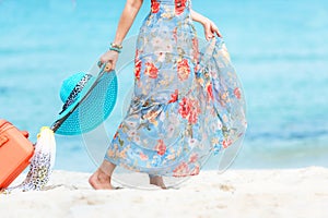 Travel Plan. Hand women traveler holding orange luggage walking on the beach. Traveler and Tourism planning trips summer vacations