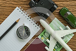 Travel planning concept with airplane, passport, compass, binoculars, pencil, paper note and Euro banknotes on wood table