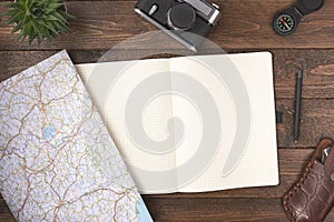 Travel planning concept. Traveler accessories. Old vintage camera with blank notepad and compass on wooden table background