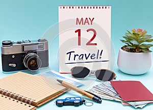 Travel planning, vacation trip - Calendar with the date 12 May glasses notepad pen camera cash passports.