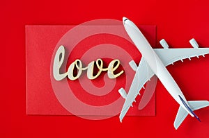 Travel planning on Valentines day . Travel concept. Inscription love and model of passenger plane on red background