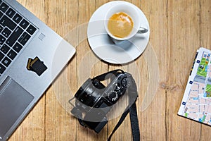 Travel planning on wooden desk table with camera, laptop, memory cards and city map. photo