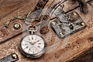 Travel with pocket watch ancient on a scratched leather suitcase in train station, ready for leaving