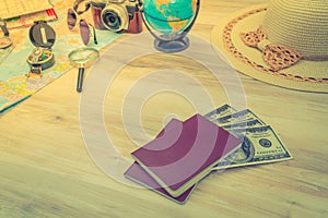 Travel preparation : compass, money, passport, road map ,hat,sunglasses,magnifying glass on wooden table .( Filtered image