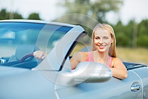 Happy young woman driving convertible car