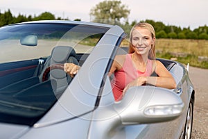 Happy young woman driving convertible car