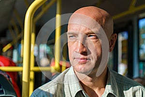 Travel safely by public transport. A young bald man looks through bus window.