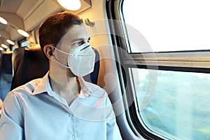 Travel safely on public transport. Young man with KN95 FFP2 face mask looking through train window. Train passenger with