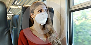 Travel safely on public transport. Young woman with KN95 FFP2 face mask looking through train window. Train passenger with