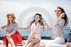 Travel, seatrip, friendship and people concept - friends sitting on yacht deck