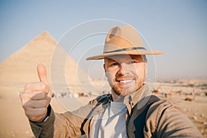 Travel selfie photo tourist man in hat background pyramid of Egyptian Giza, sunset Cairo, Egypt