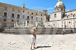 Travel in Sicily. Back view of young beautiful woman walking near the monumental Praetorian Fountain in Palermo, Italy