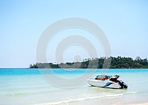 A travel speed boat with red life jacket vests on the shore near a white clean sandy beach on blue sea.