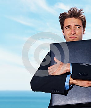 Travel, stress and business man with briefcase at beach with fear, risk or lost in nature on blue sky background