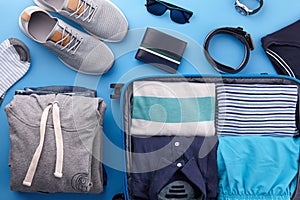 Travel suitcase with clothes on blue background