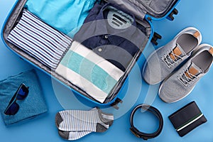 Travel suitcase with clothes on blue background