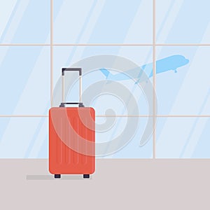 Travel suitcase in empty waiting area of airport terminal, against background of large windows, take-off of plane in background