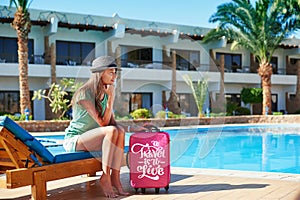 Travel, summer holidays and vacation concept - Beautiful woman walking near hotel pool area with red suitcase in Egypt