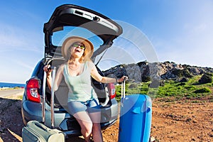 Travel, summer holidays and vacation concept - Young woman with suitcases on car trip.