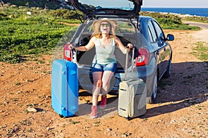 Travel, summer holidays and vacation concept - Young woman with suitcases on car trip.